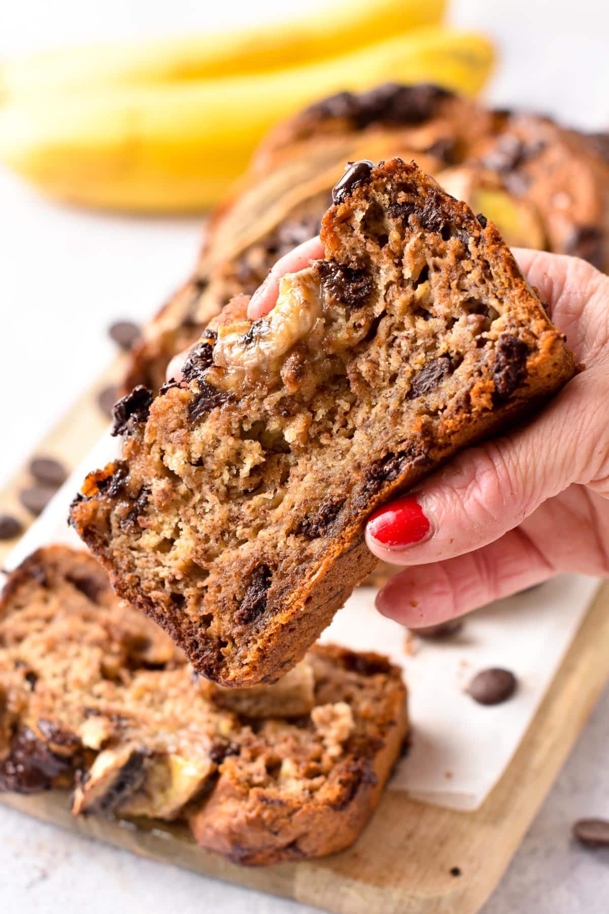 Vegan Chocolate Chip Banana Bread slice held in front of the bread.