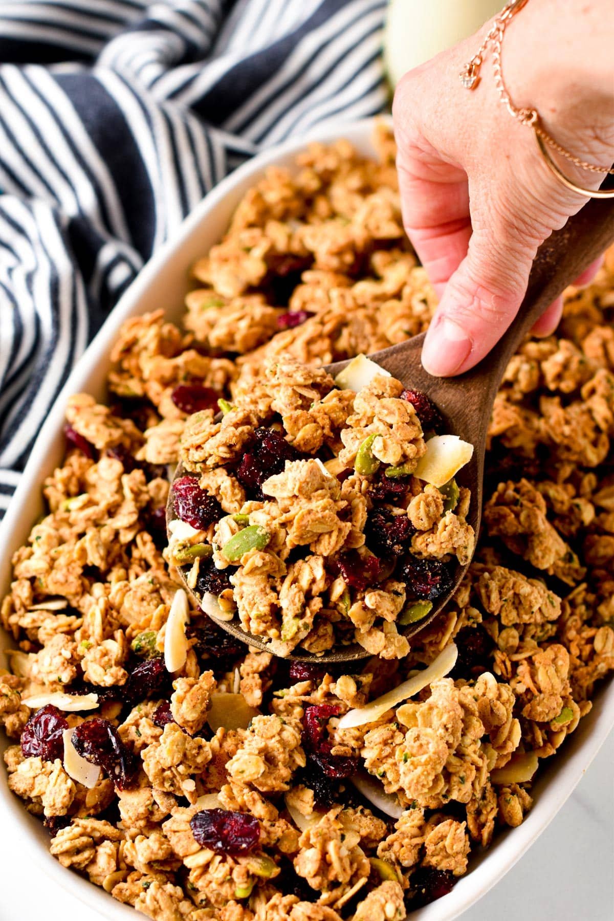 High-protein granola in  a large dish with a wooden spoon.