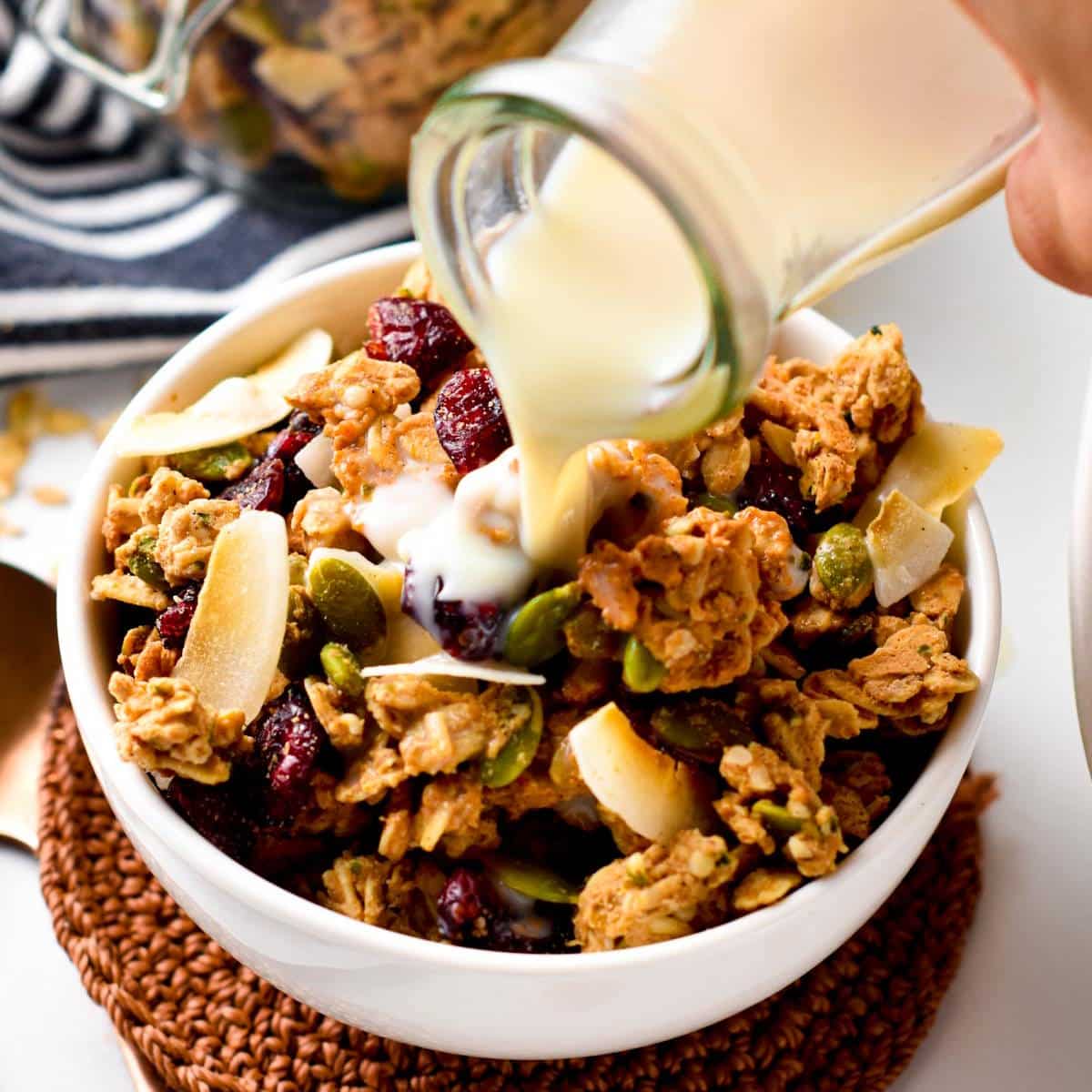 Pouring almond milk on high-protein granola in a bowl.