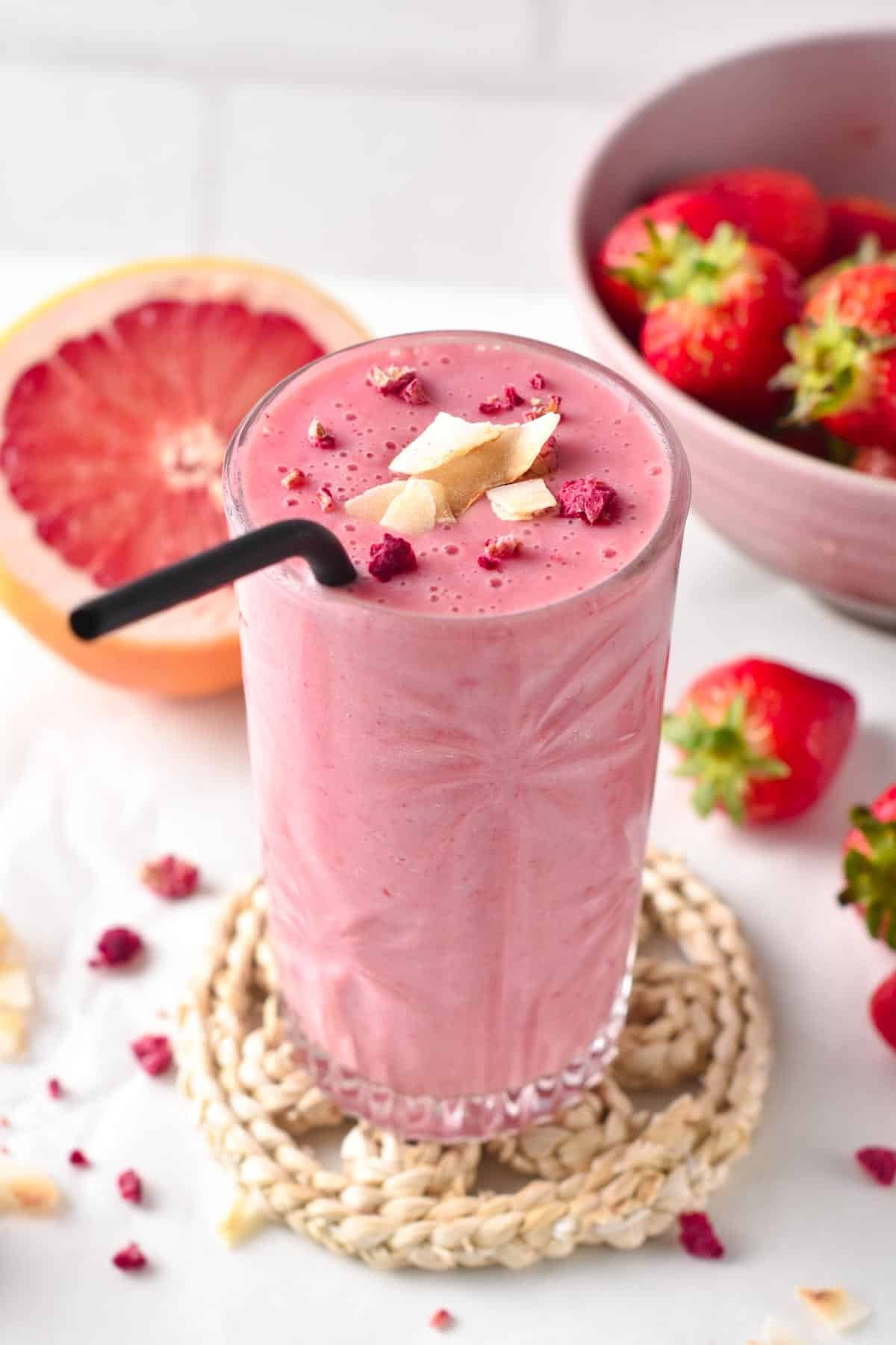 Grapefruit smoothie in a tall glass with a black metal straw,