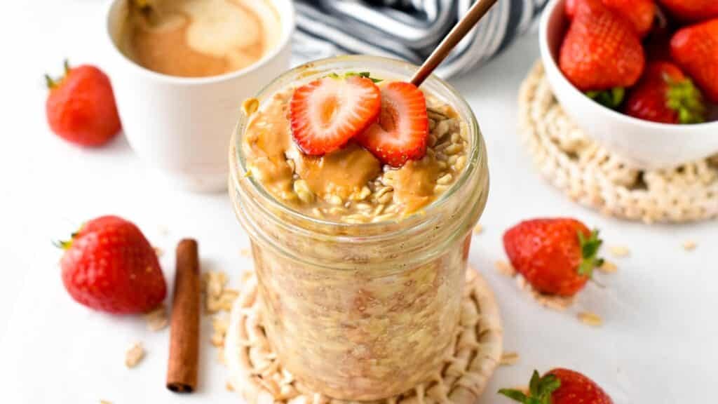 Overnight Oats with Water in a jar with strawberry and peanut butter on top.
