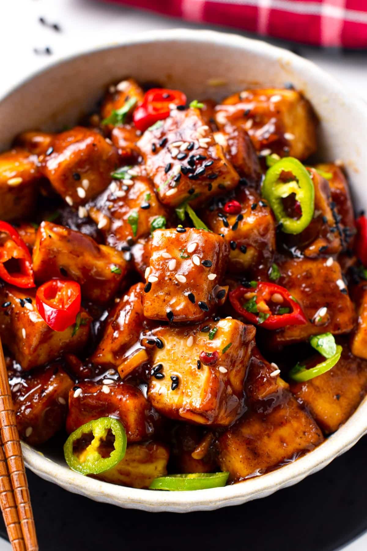 Szechuan Tofu decorated with sliced chili and sesame seeds.