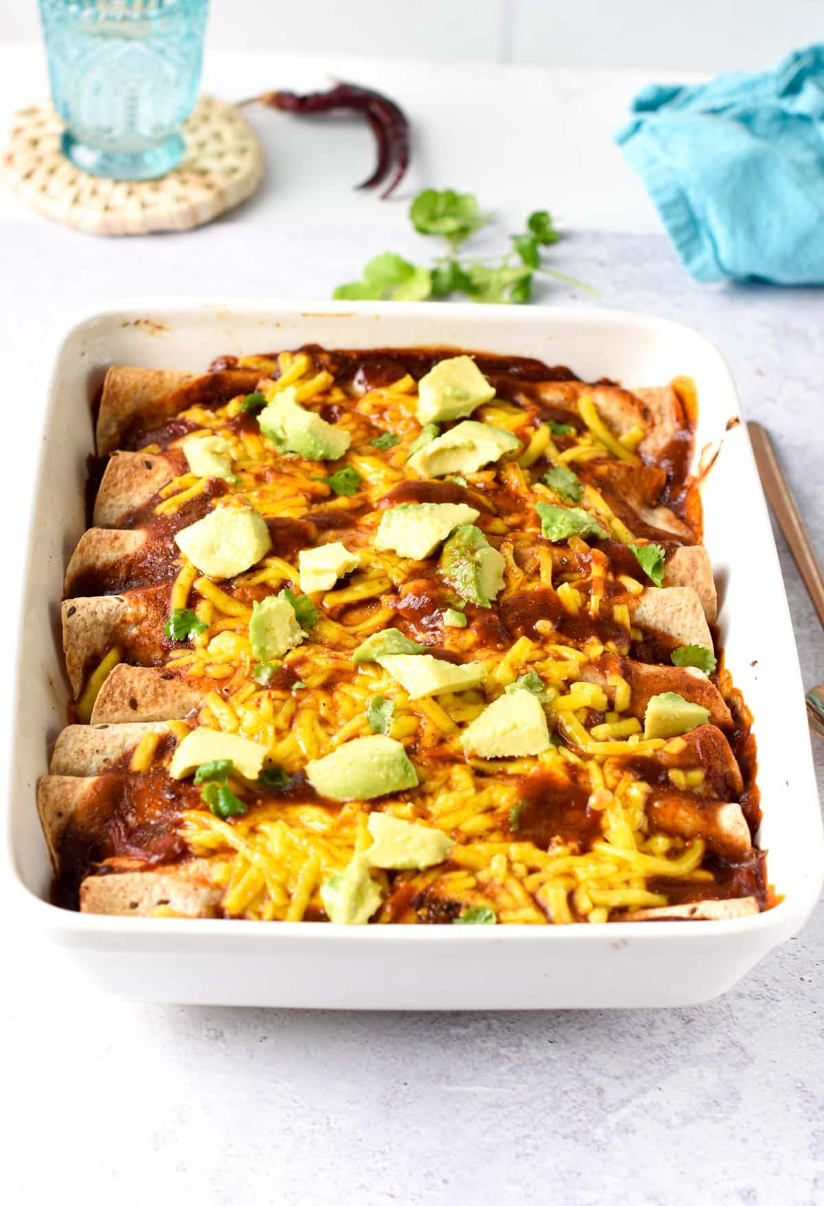 Vegan Enchiladas cooked in a large baking dish and decorated with fresh guacamole.