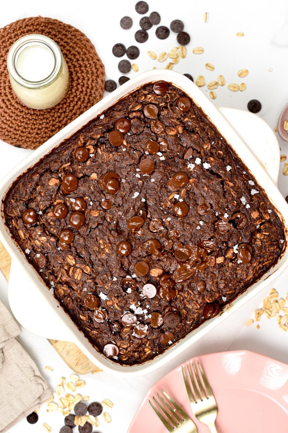 Brownie Baked Oatmeal in a square ceramic pan next to a jar of plant-based milk.