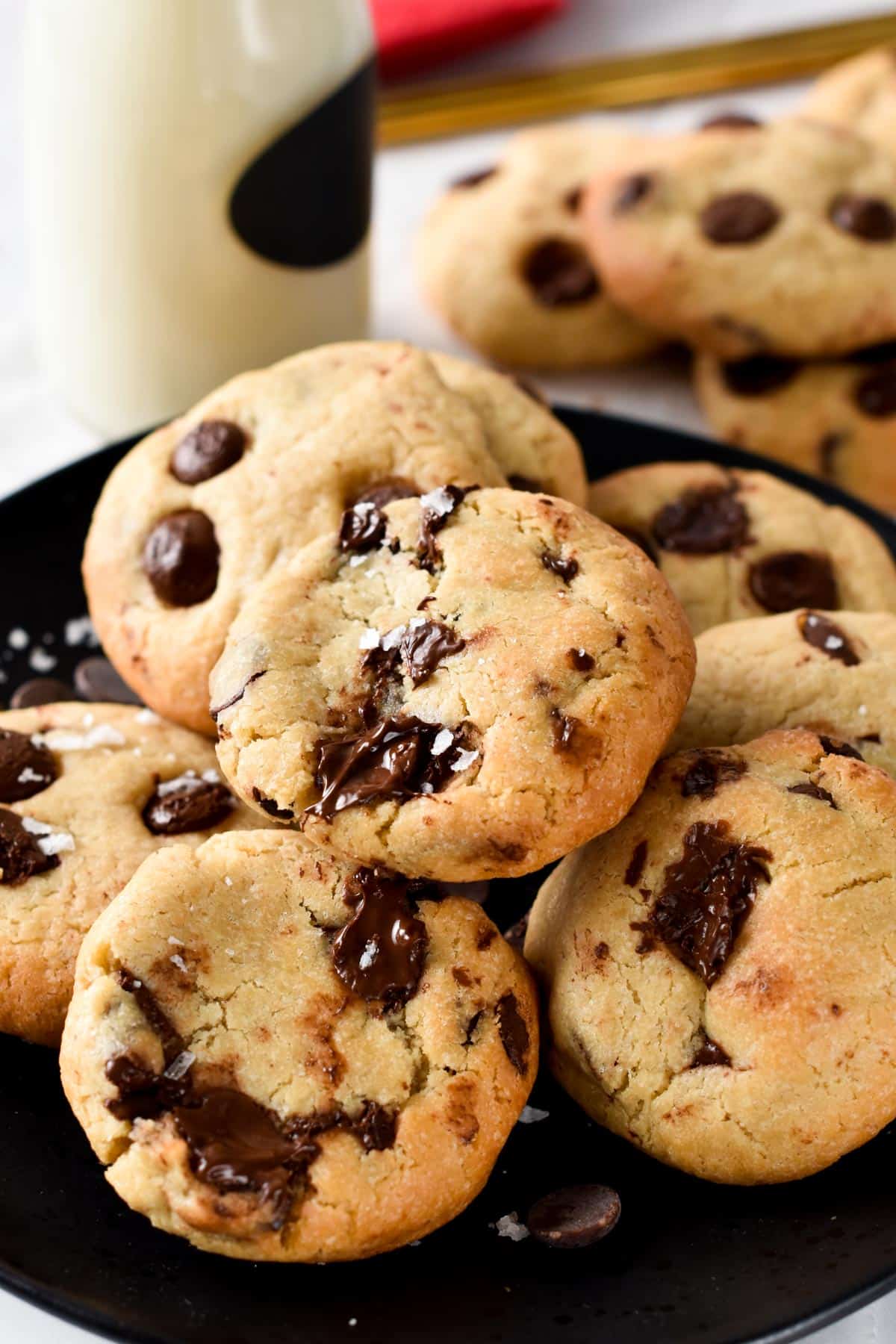 A black plate filled with eggless chocolate chip cookies decorated with salt flakes.