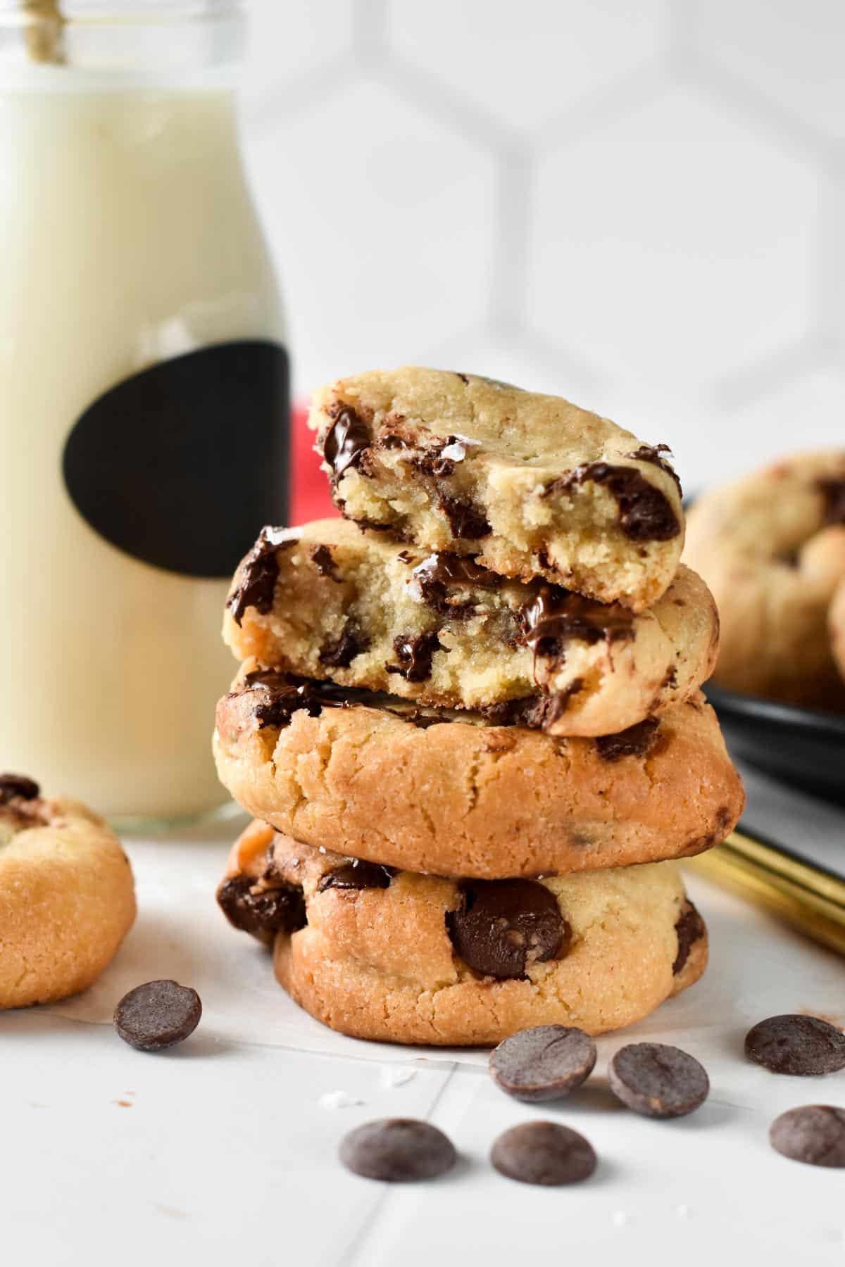 Stack of eggless chocolate chips cookies in front of a glass bottle of almond milk.