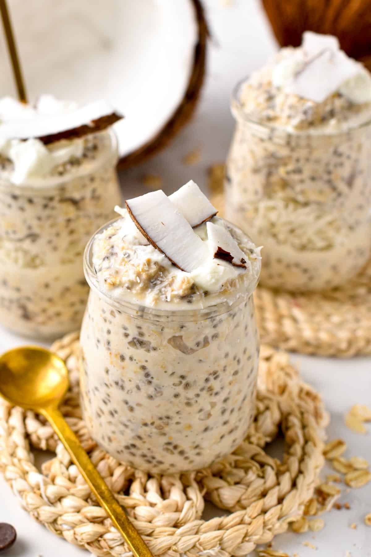 Overnight Oats With Coconut Milk in three jars next to a golden spoon.