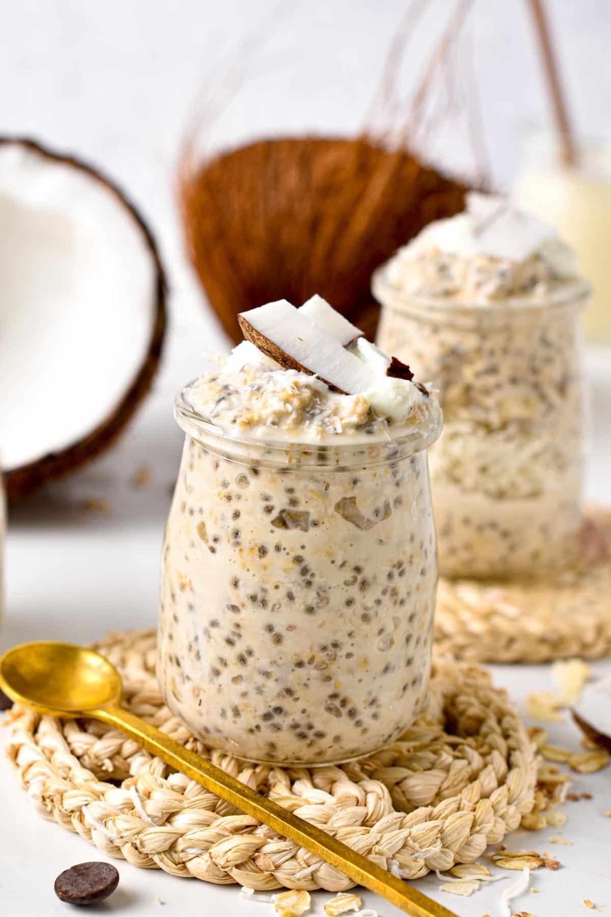 Overnight Oats With Coconut Milk in two jars decorated with fresh coconut.