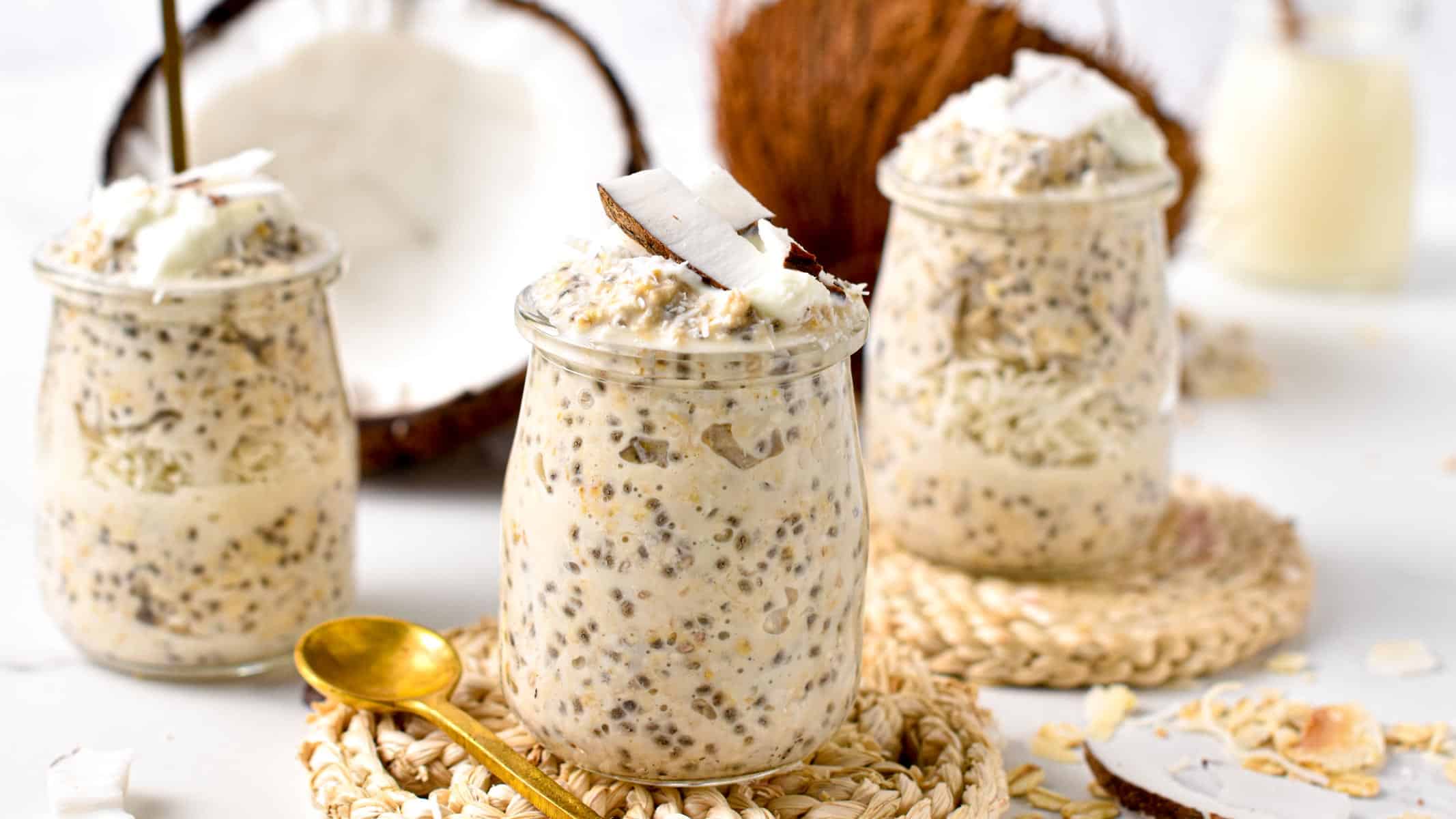 Overnight Oats With Coconut Milk in three jars decorated with fresh coconut.