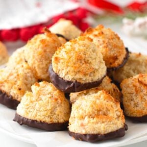 a plate filled with a stack of vegan coconut macaroons with toasted coconut and chocolate dipped