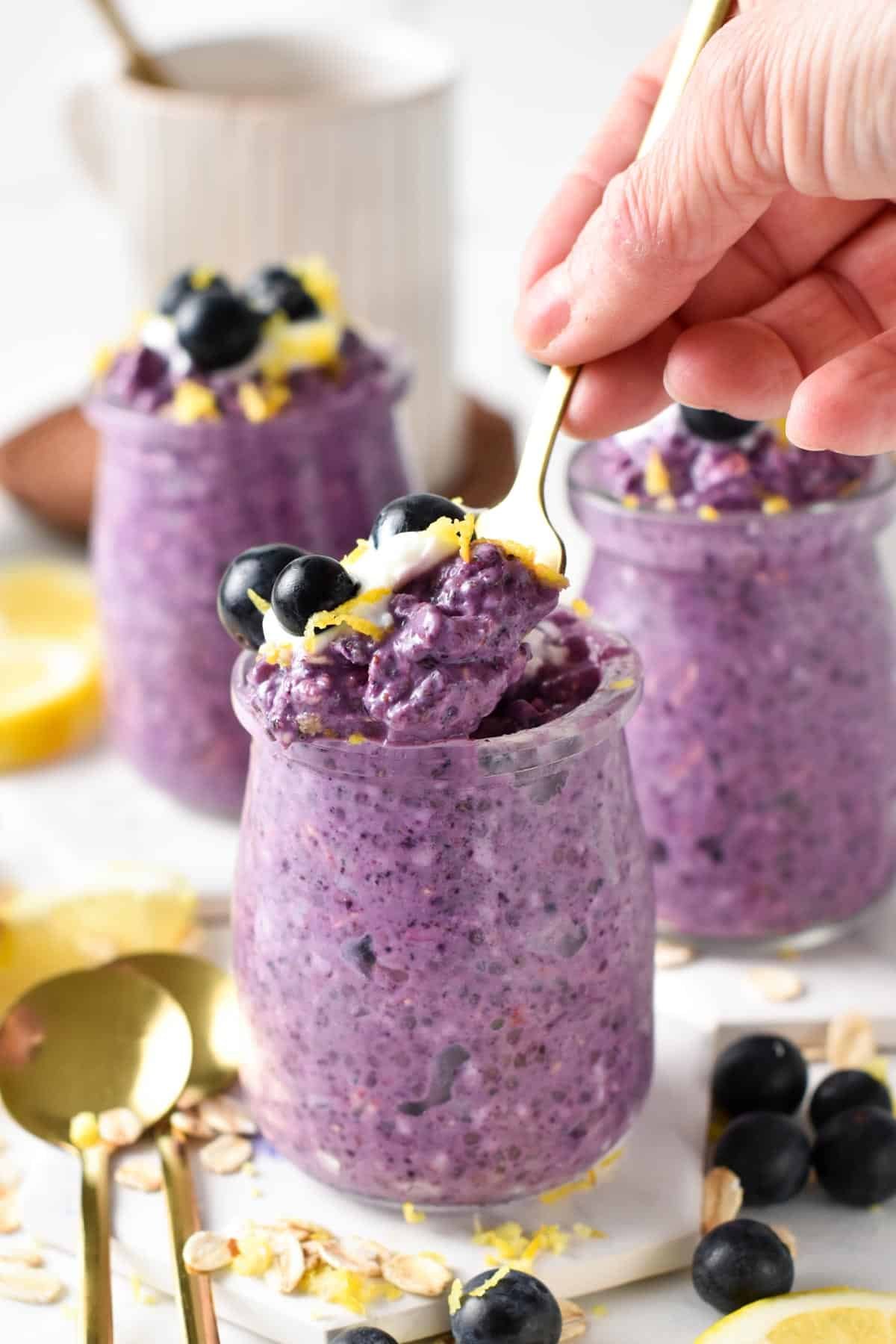 Golden spoon taking a portion of blueberry overnight oats off their jar.