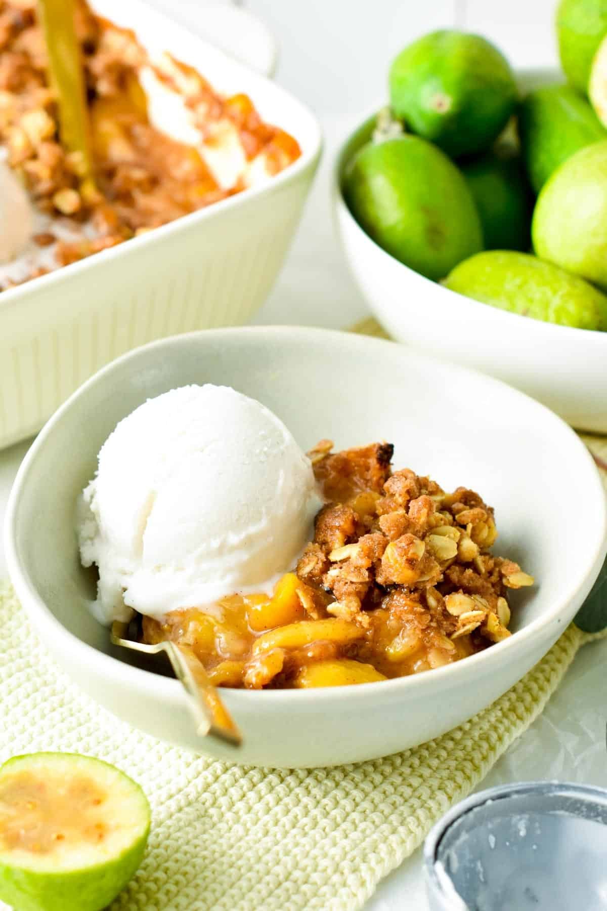 A serving of feijoa crumble on a small bowl with a scoop of vanilla ice cream.