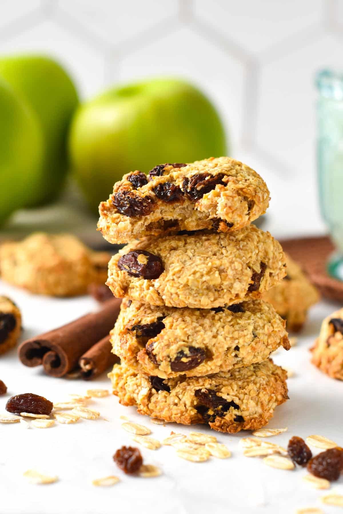 3-Ingredient Oatmeal Raisin Cookies stacked in front of cinnamon sticks.