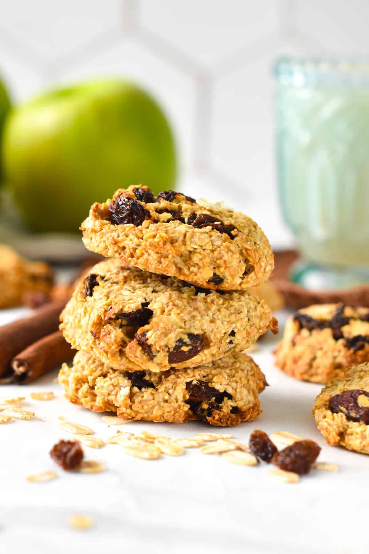3-Ingredient oatmeal raising cookies stacked on a table in front of green apples.
