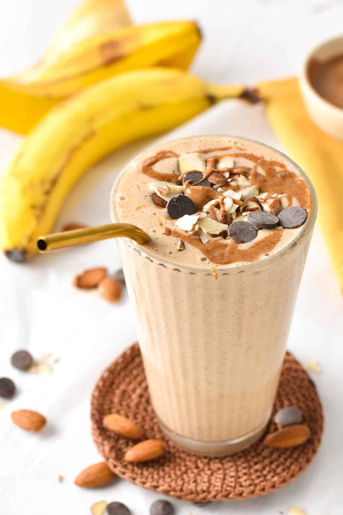 Banana Almond Butter Smoothie  in a tall glass with a golden straw.