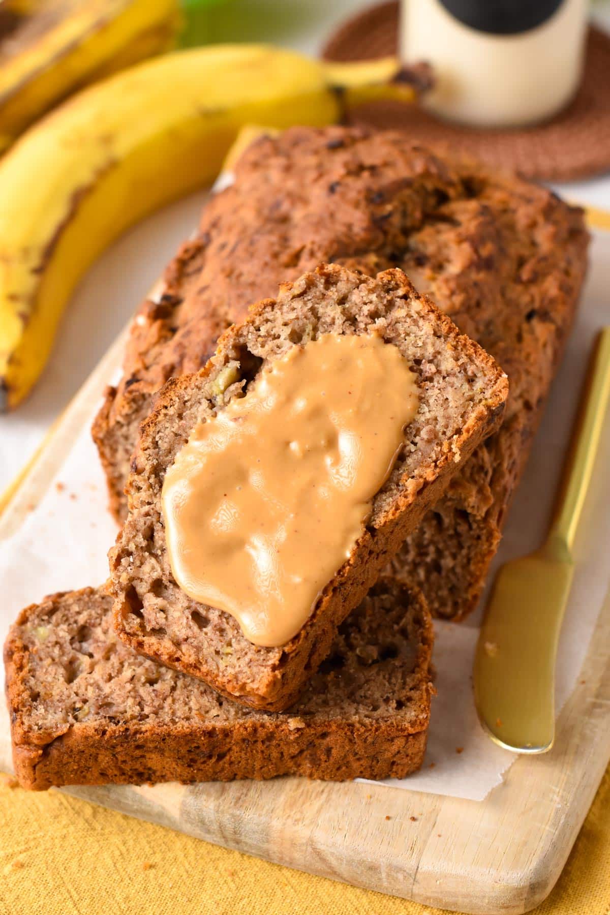 Slices of No Sugar Added Banana Bread stacked with one covered with peanut butter.