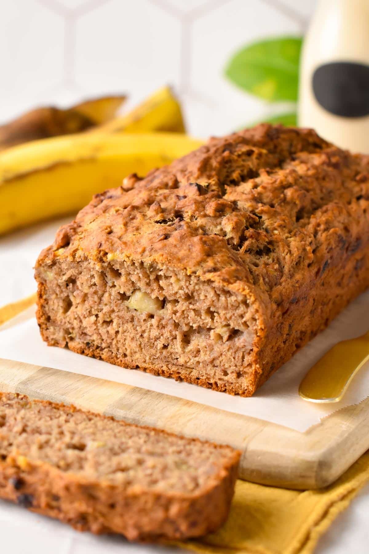 No Sugar Added Banana Bread loaf on a chopping board with a golden knife.