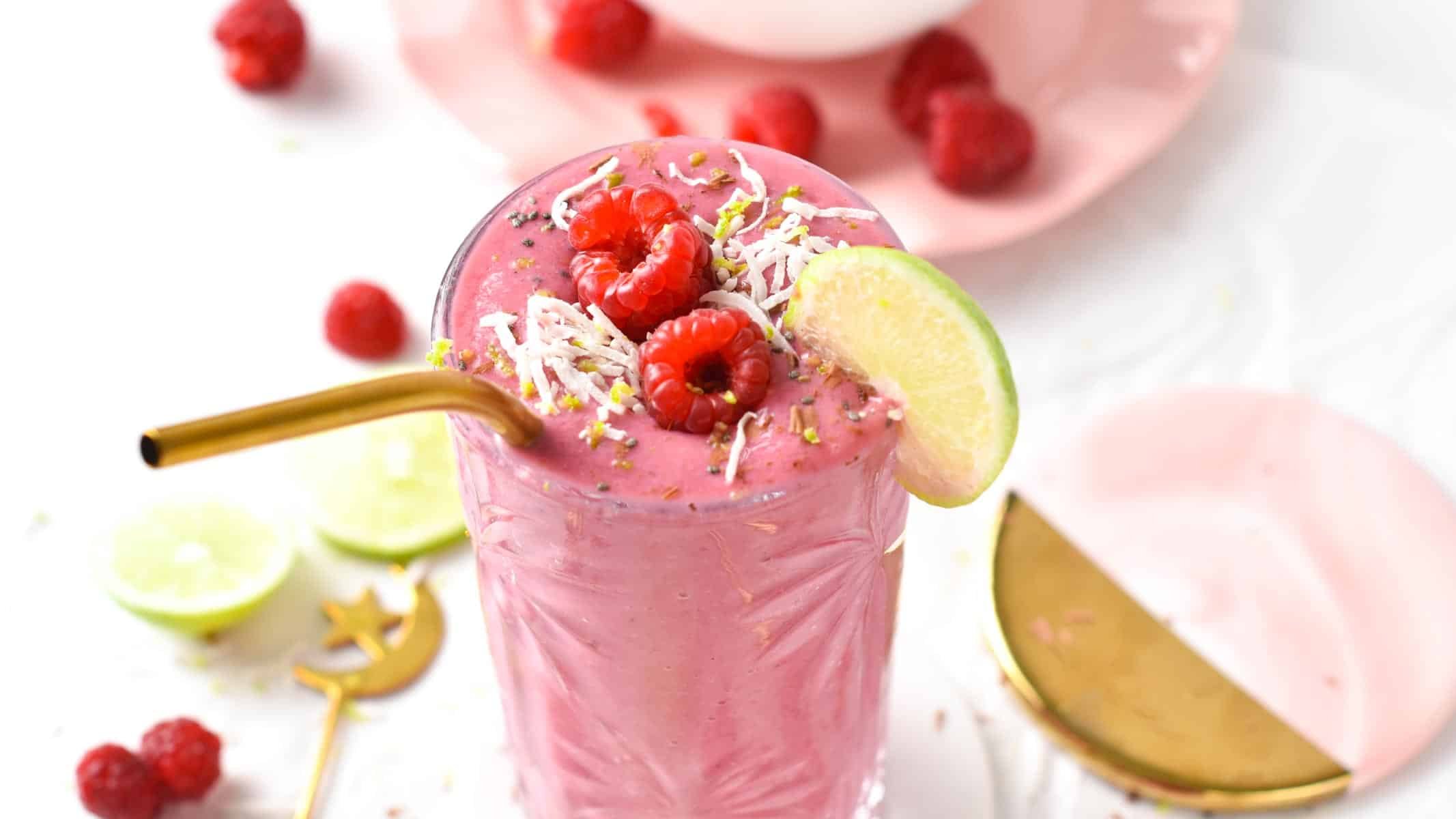 Raspberry Smoothie decorated with a slice of lime, fresh raspberries, and shredded coconut.