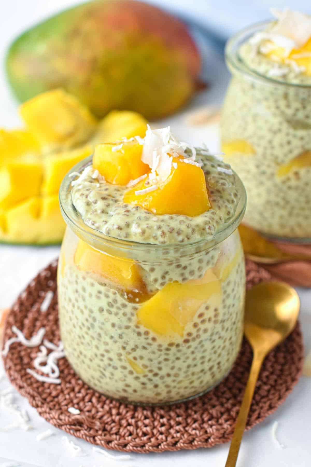 Mango chia pudding decorated with fresh mango and coconut flakes on a coaster.