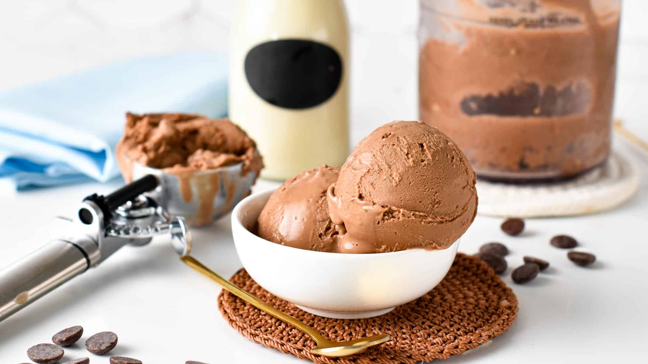 Ninja Creami Protein Ice Cream in a bowl on a coaster with an ice cream scoop next to it..