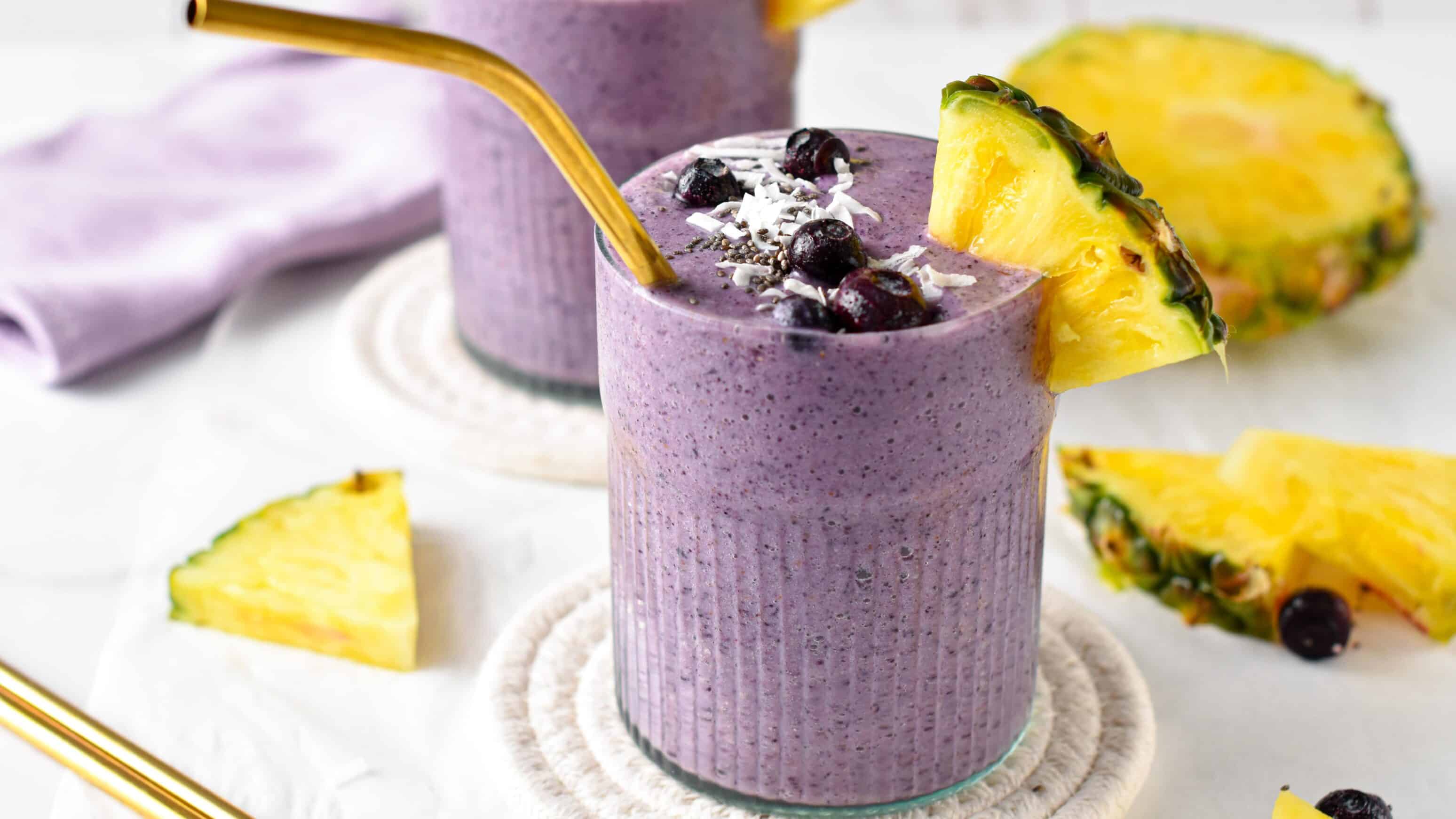 Blueberry Pineapple Smoothie in a small glass with a golden straw