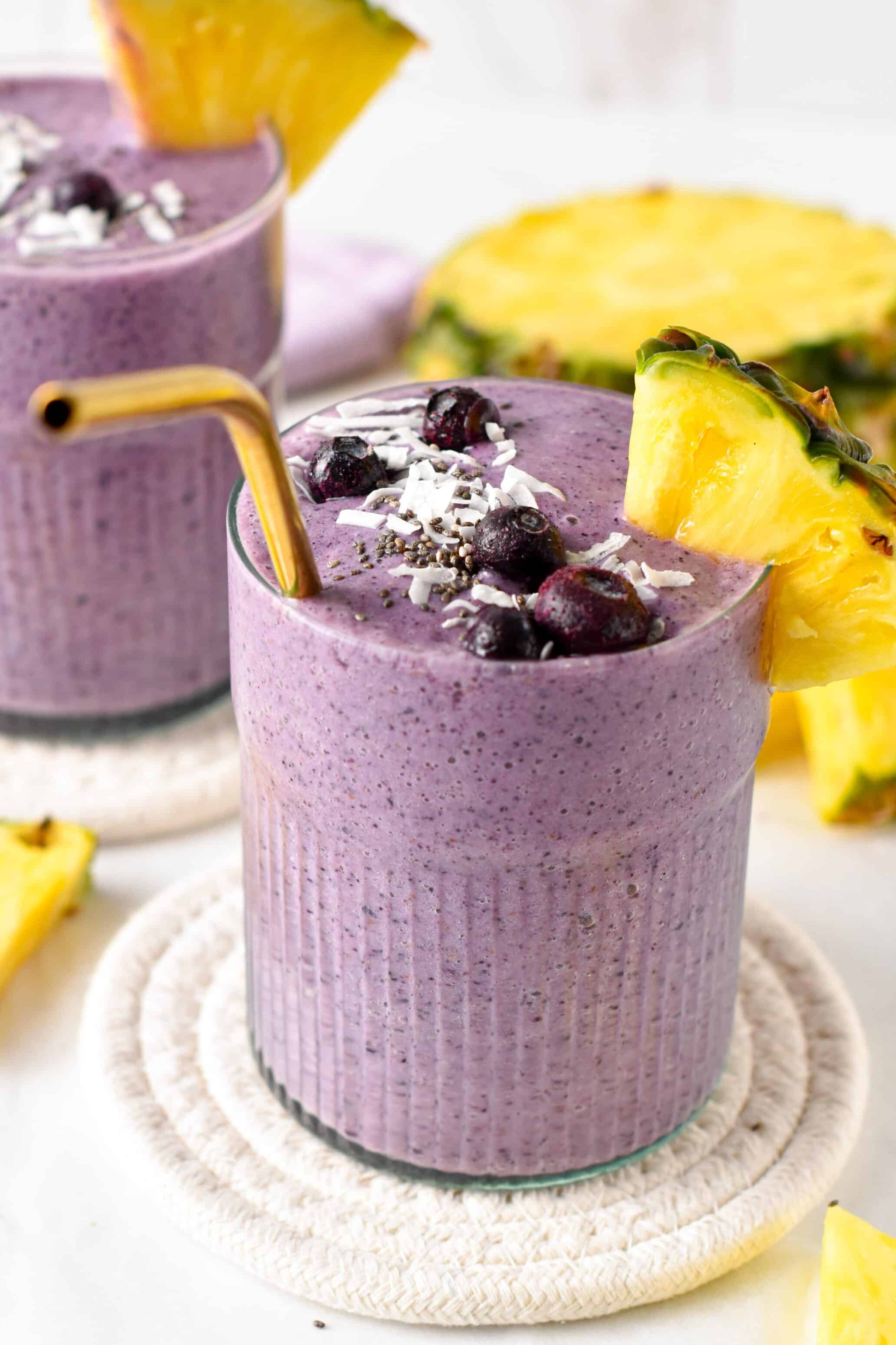 Blueberry Pineapple Smoothies in two glasses decorated with fresh blueberries and a slice of pineapple