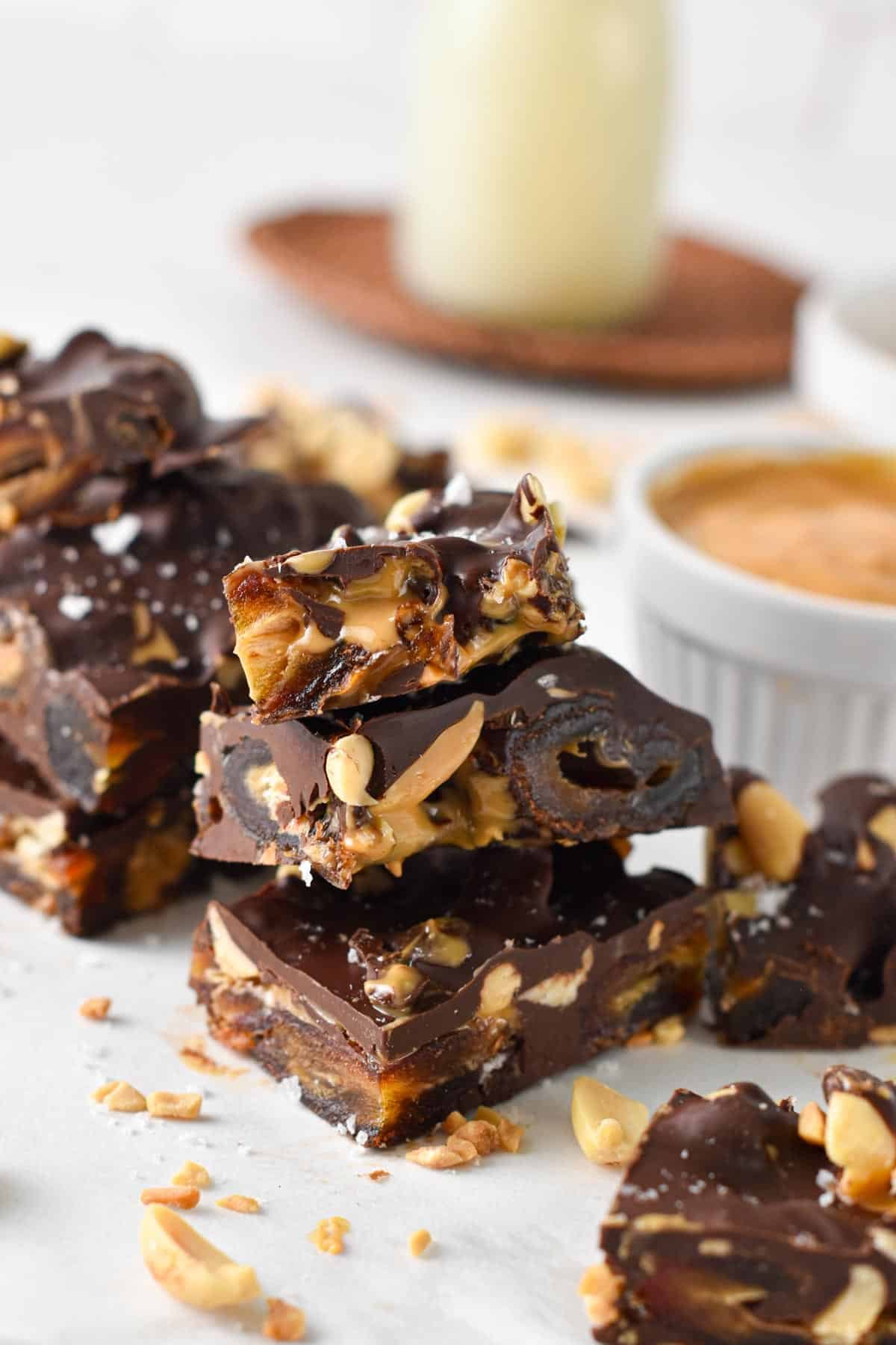 Close-up view of cut pieces of date bark on a white table with a peanut butter jar in the background.