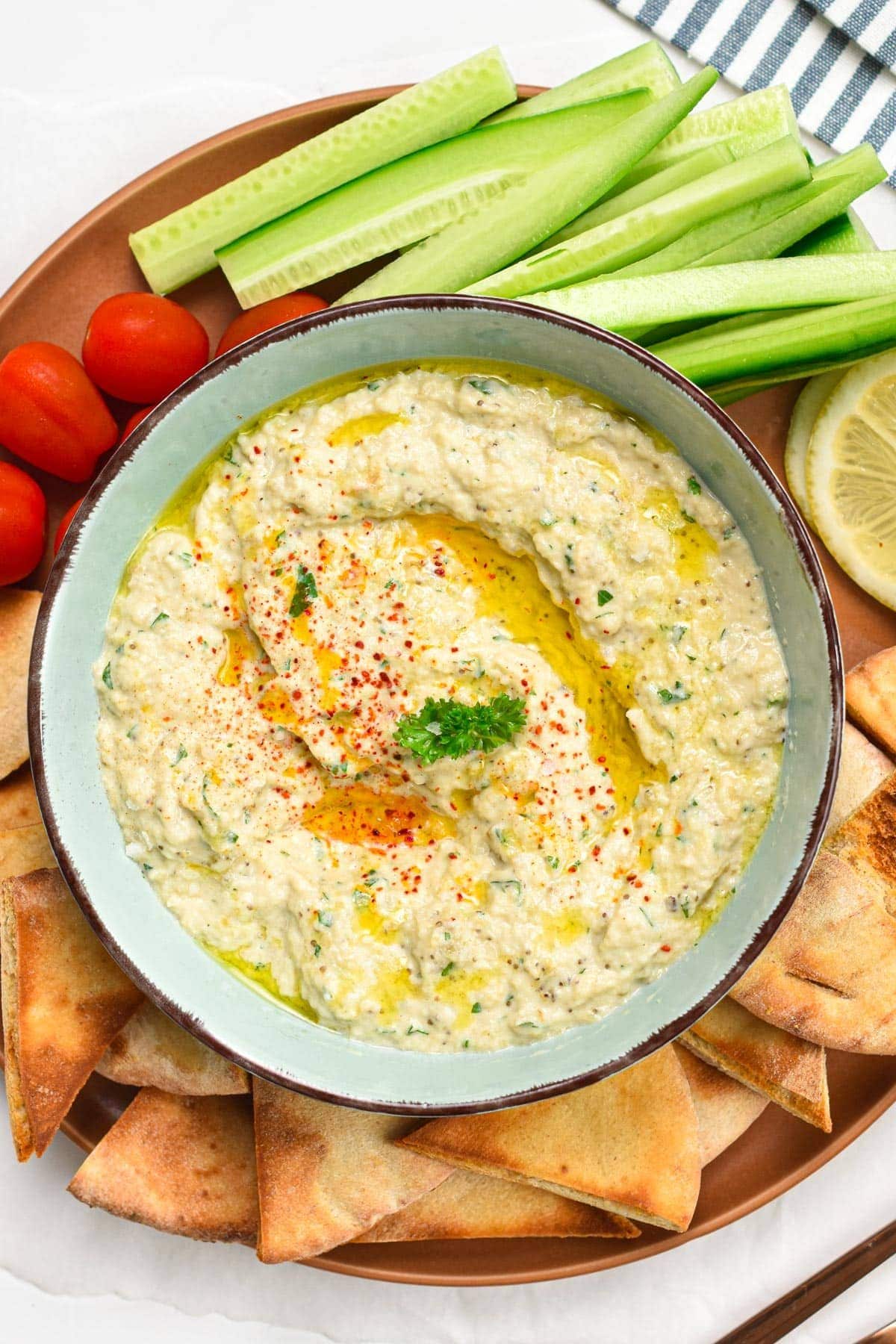 Bowl with vegan baba ganoush on a plate full of pita chips.