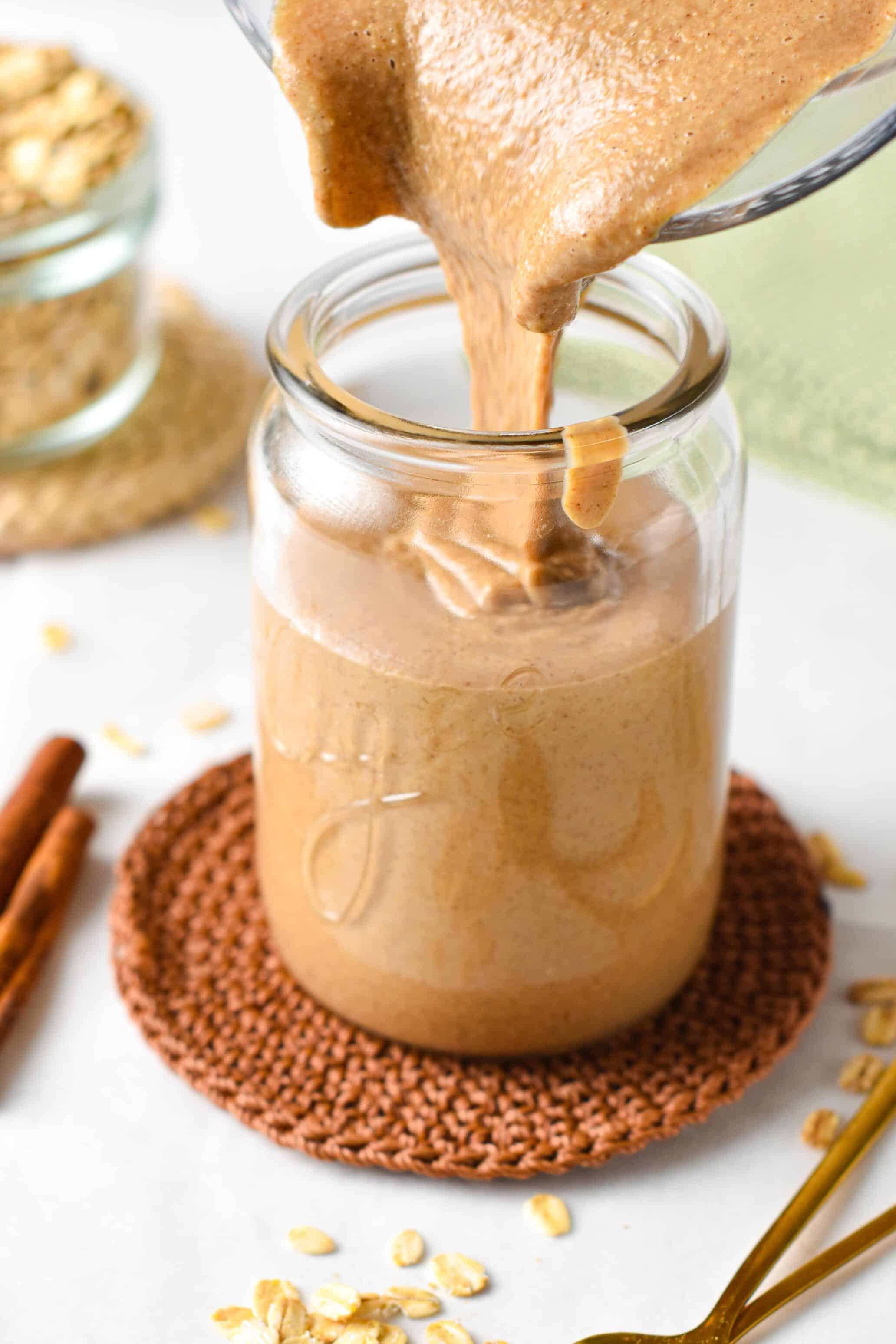 Pouring granola butter into a glass container.