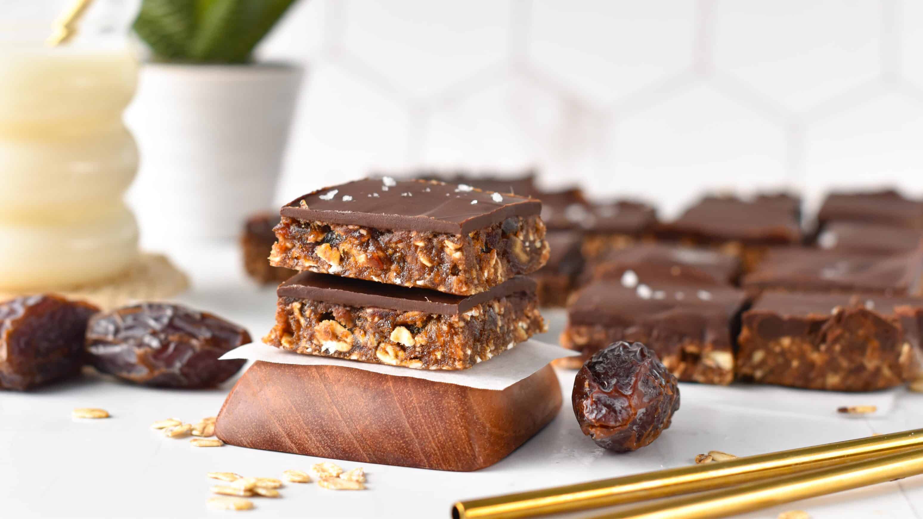 Healthy date bars cut into square, stacked, next to golden straws.