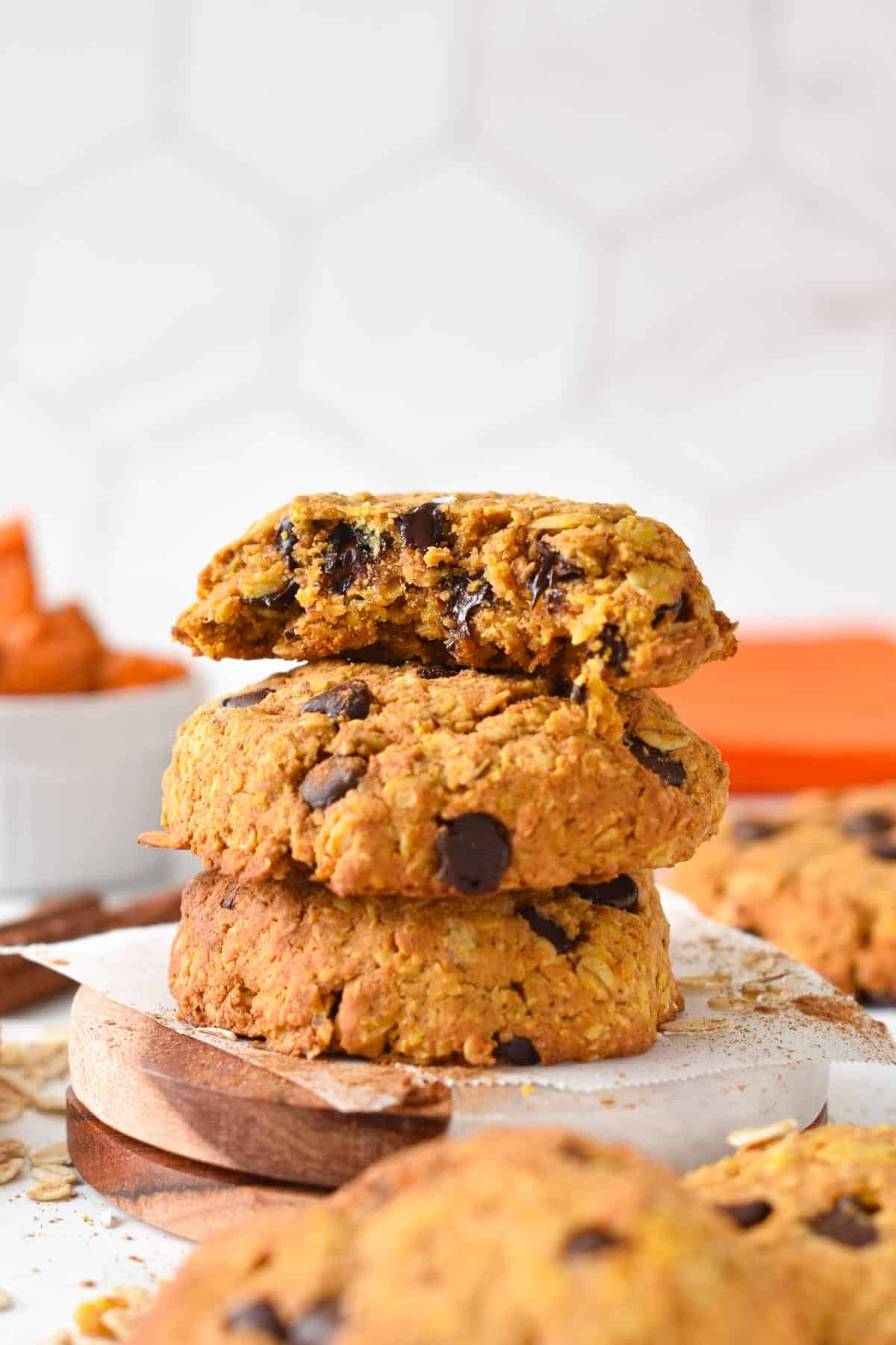 A stack of pumpkin protein cookies with chocolate chips presented on a small coaster,