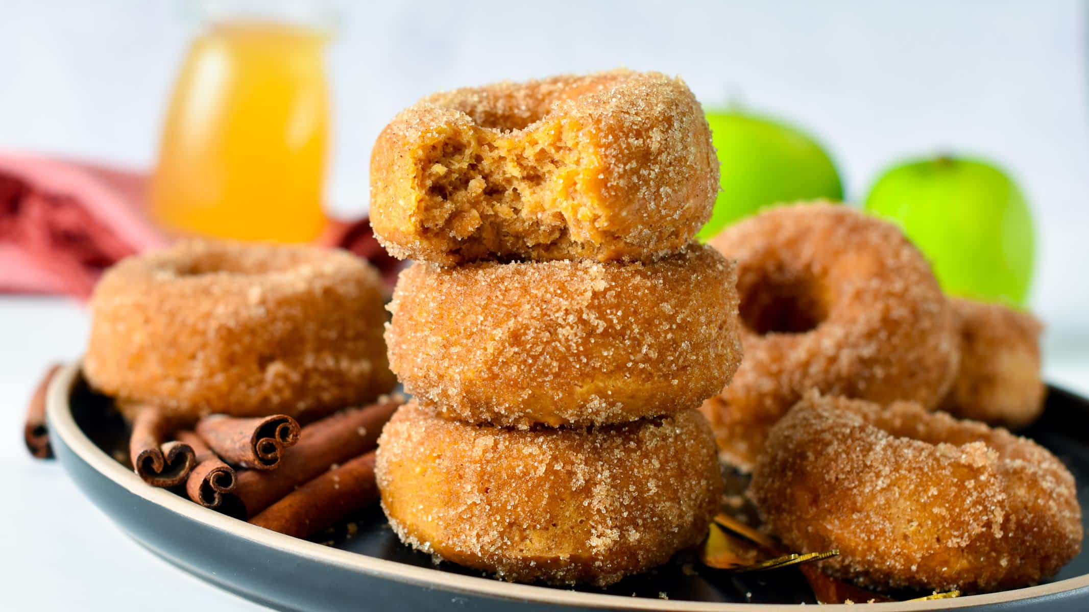 A stack of vegan apple cider vinegar donuts on a black plate.