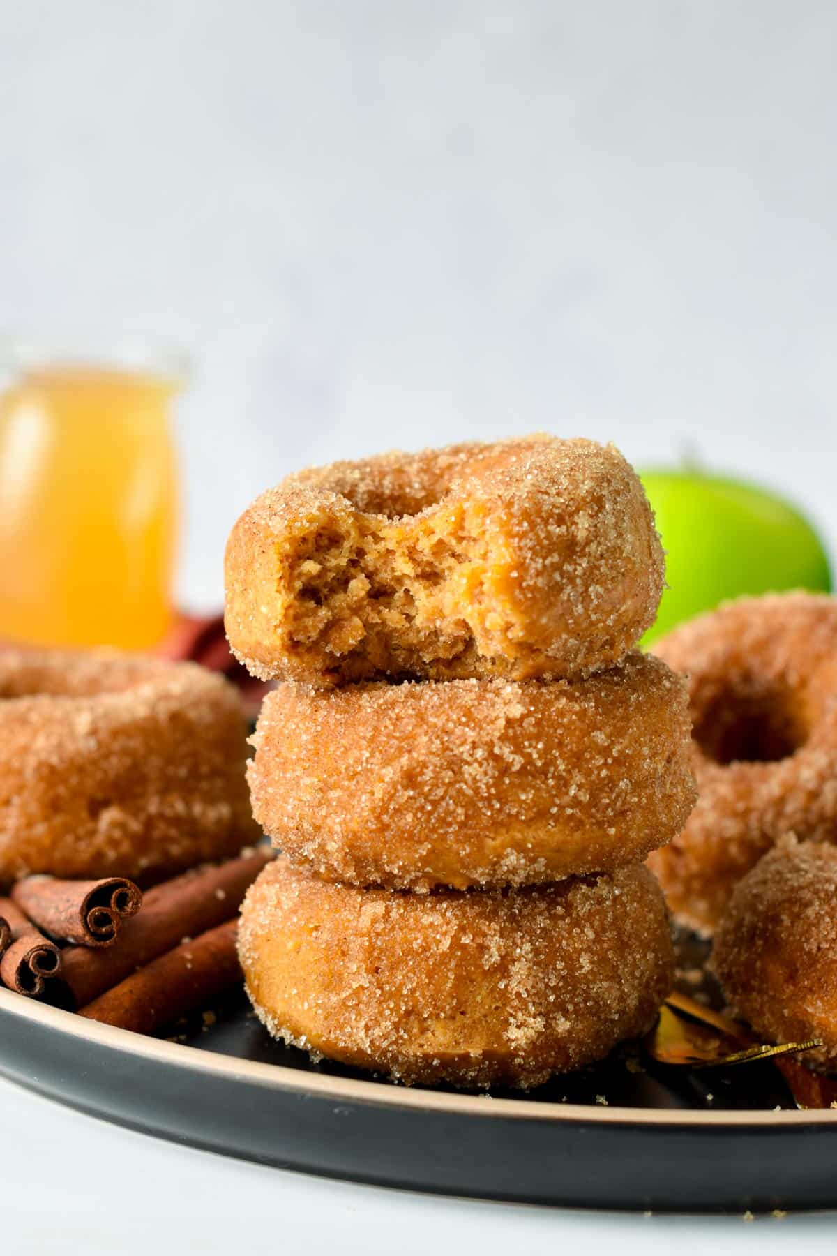 A stack of vegan apple cider vinegar donuts. next to cinnamon sticks.