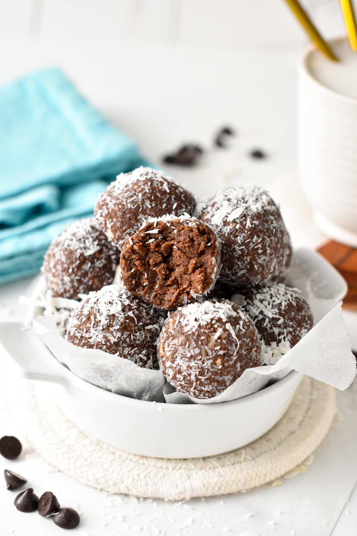 Several Chocolate Coconut Protein Balls on a small presentation ramekin on a white table.