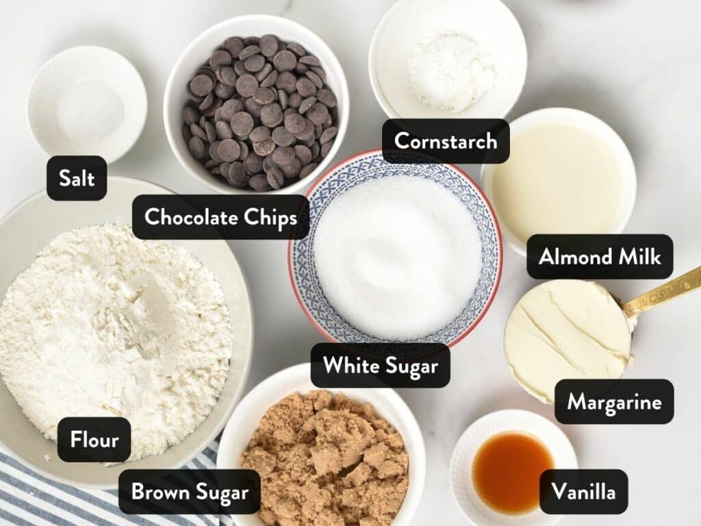 Ingredients for Eggless Chocolate Chip Cookies in small bowls and cups with labels.