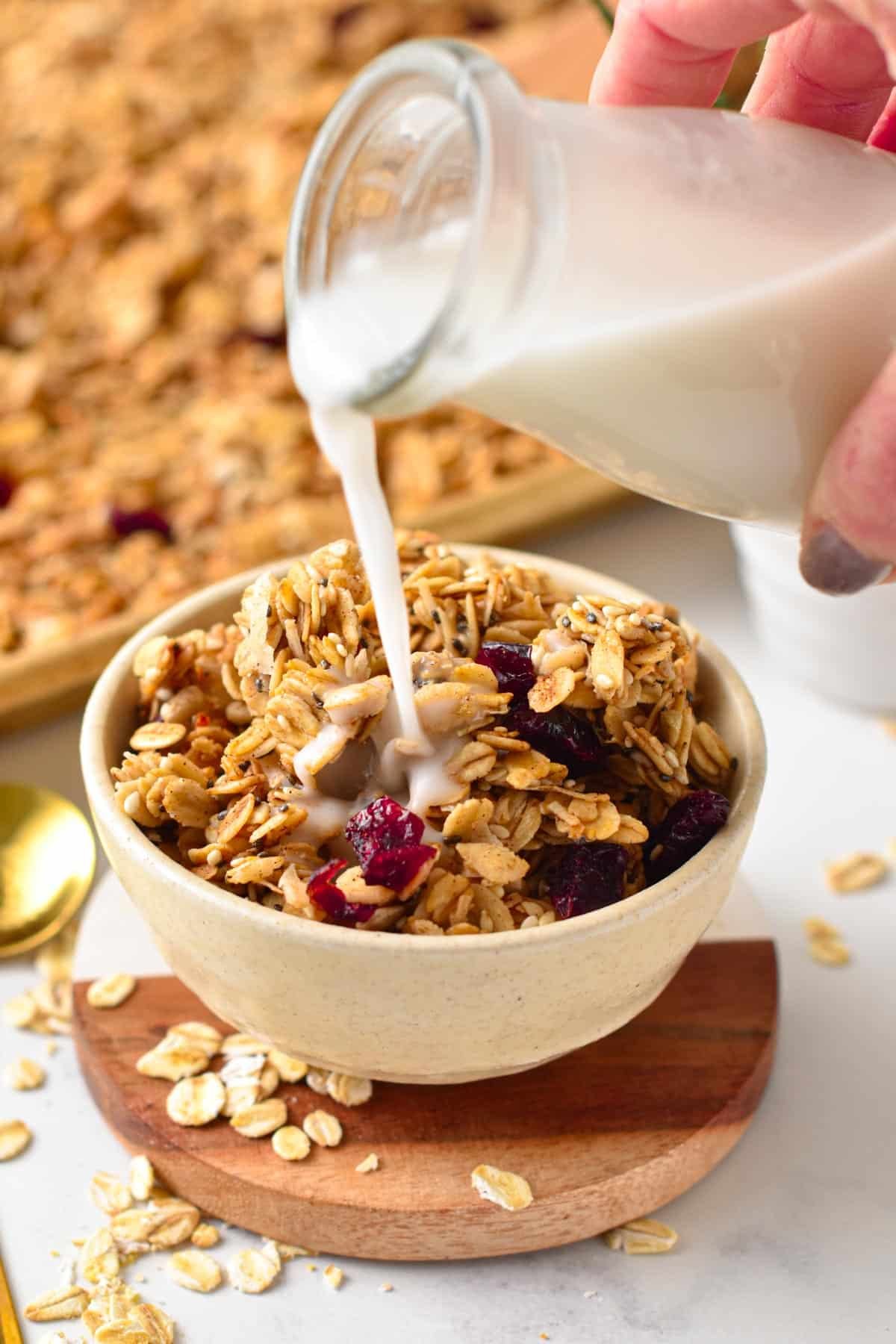 Pouring coconut milk on a bowl of nut-free granola.