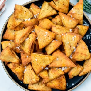 A plate of baked pita chips decorated with sea salt.