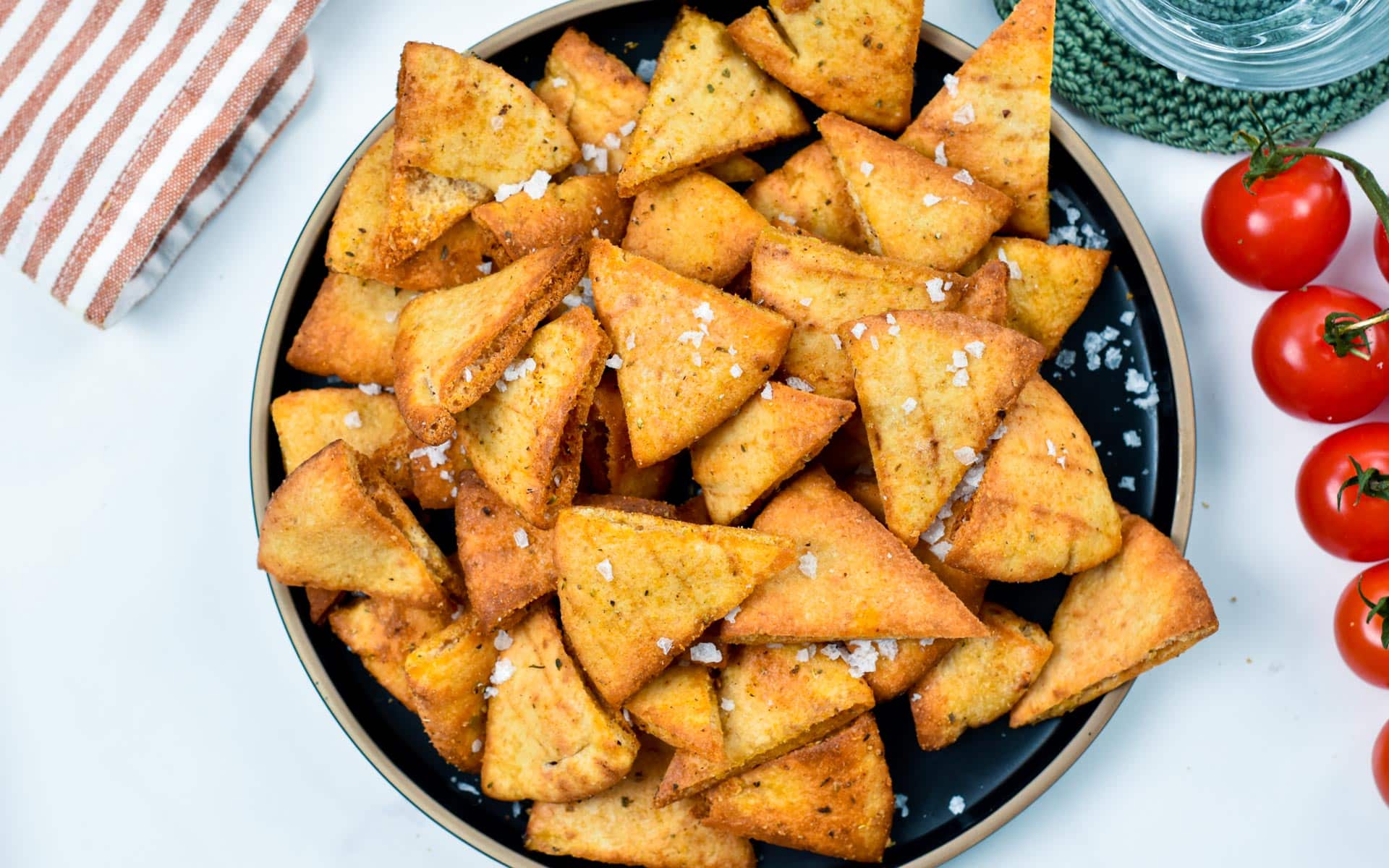 A plate of baked pita chips decorated with sea salt.