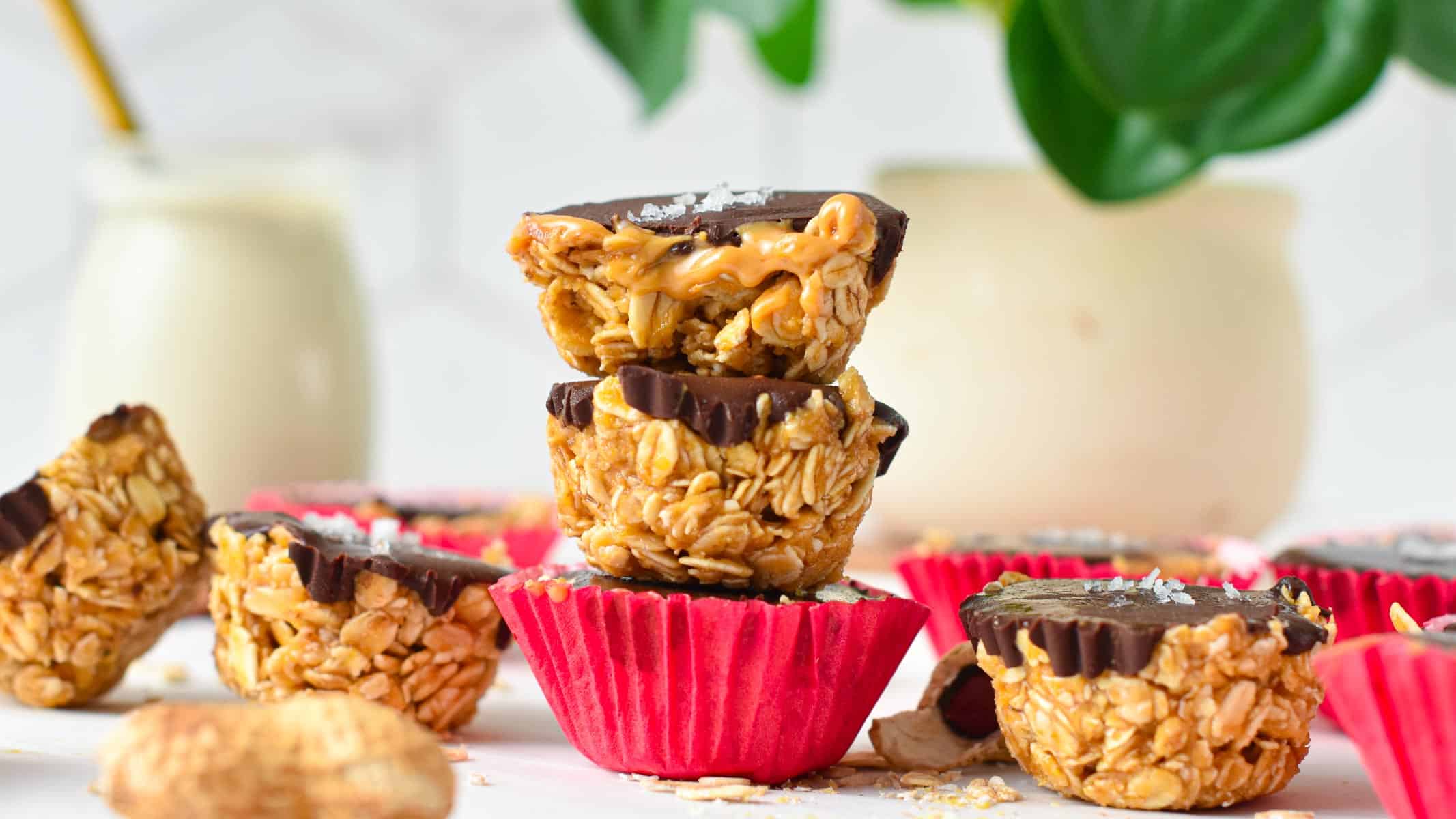 a stack of three no-bake peanut butter oat cups with the one on top half cut showing the runny peanut butter filling