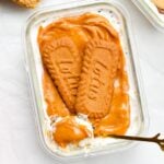 a rectangle glass container picture from the top, filled with biscoff overnight weetbix and topped with yogurt, biscoff and biscoff biscuits and a golden spoon showing the inside of the recipe