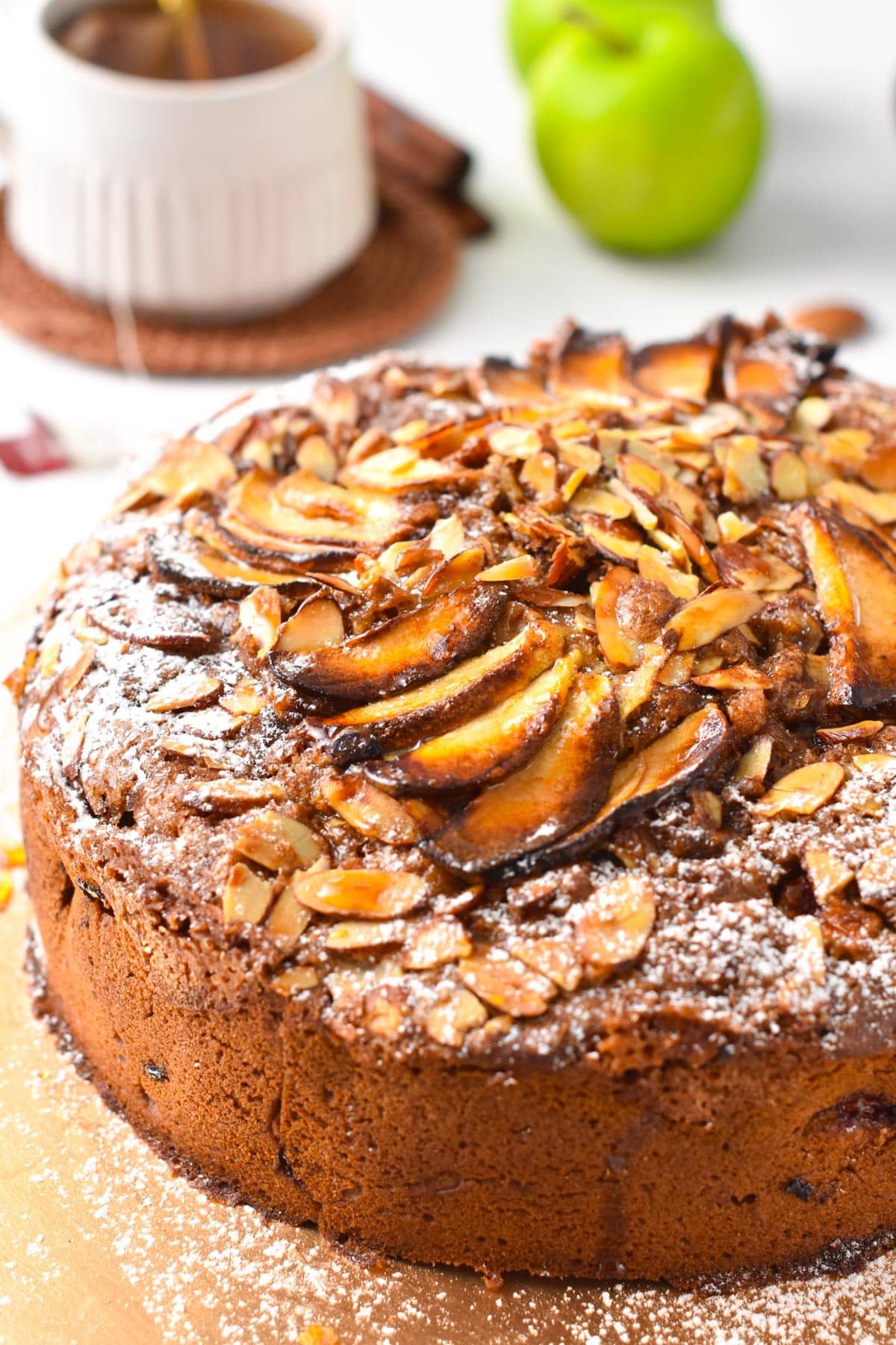 A vegan apple cake topped with slivered almonds and apple slices.