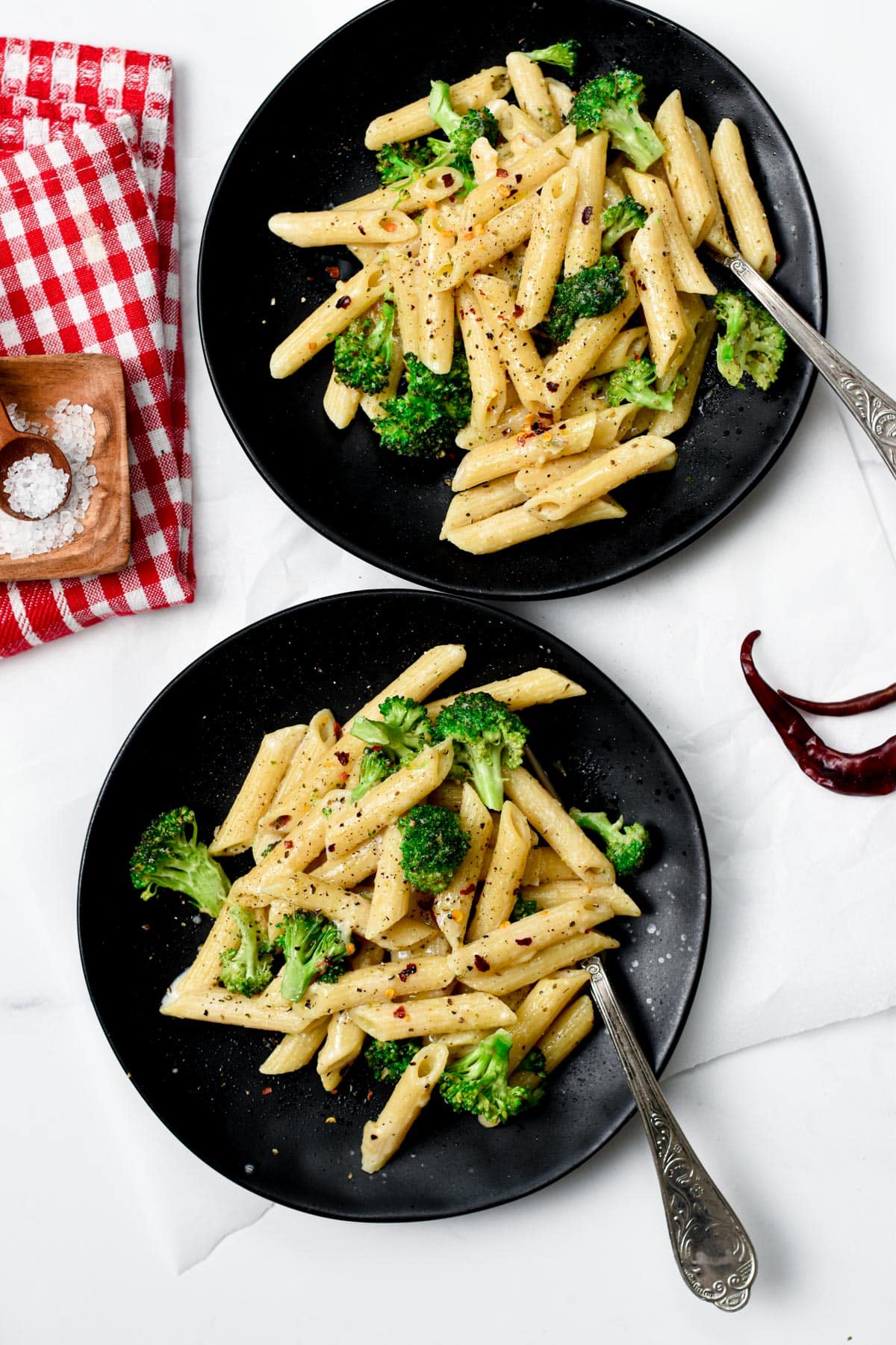 Vegan Broccoli Pasta in two small black plates with forks.