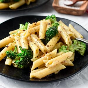 Vegan Broccoli Pasta on a black plate with a fork.