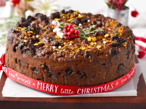 a Vegan Christmas Cake decorated with vegan golden sprinkles and Christmas ribbon