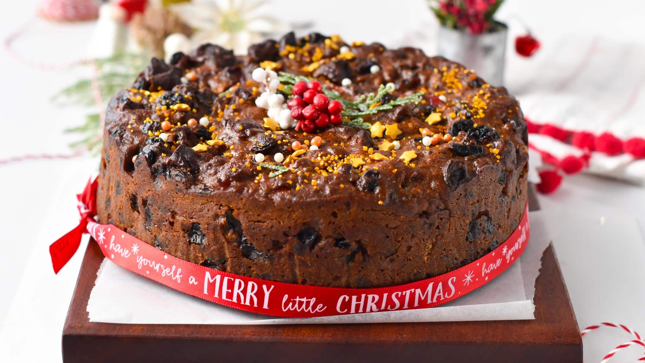 a Vegan Christmas Cake decorated with vegan golden sprinkles and Christmas ribbon