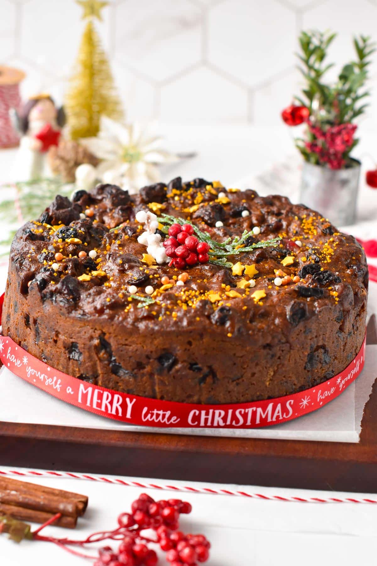 A Vegan Christmas Cake decorated with vegan golden sprinkles and Christmas ribbon