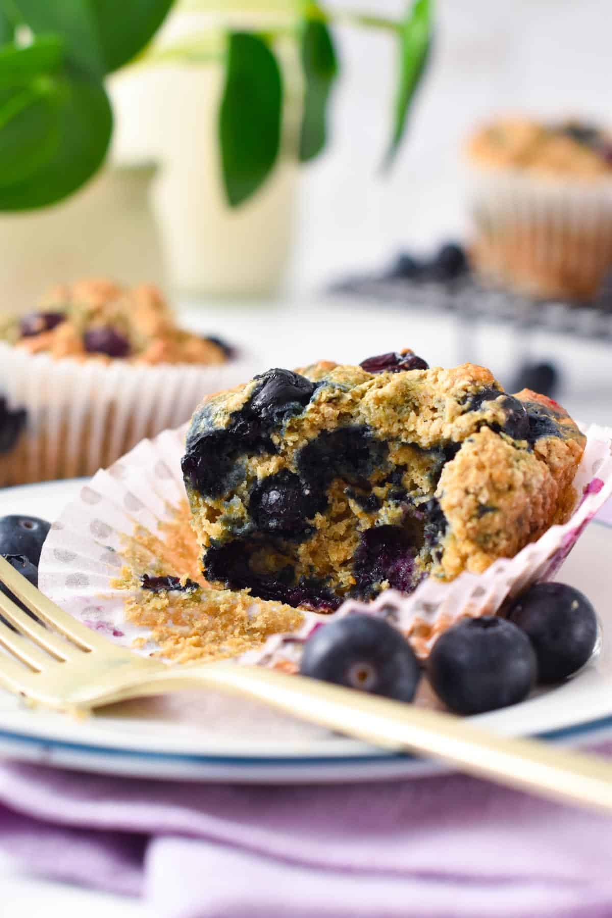 The inside of a Vegan Gluten Free blueberry Muffins on a plate decorated with fresh blueberries.
