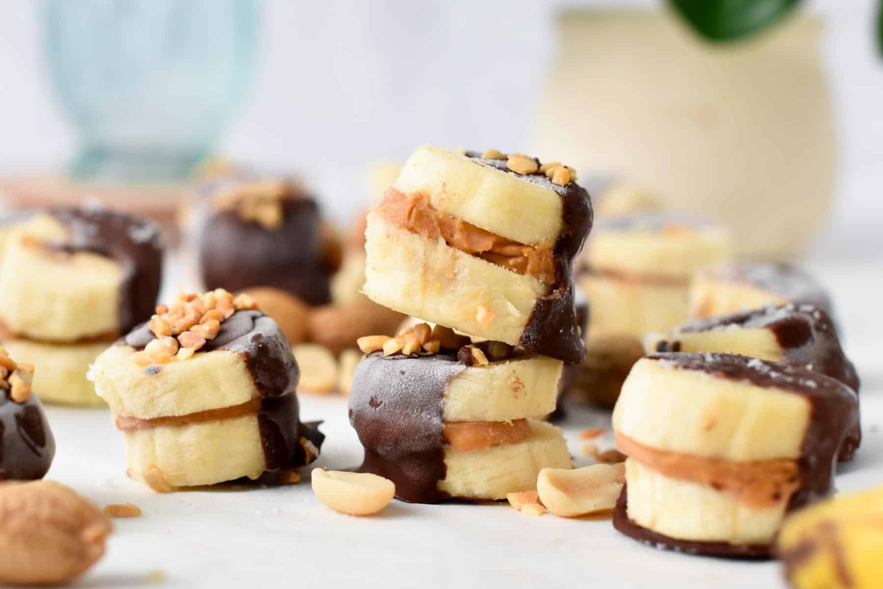 a stack of banana bites filled with peanut butter in the center and half covered with dark chocolate