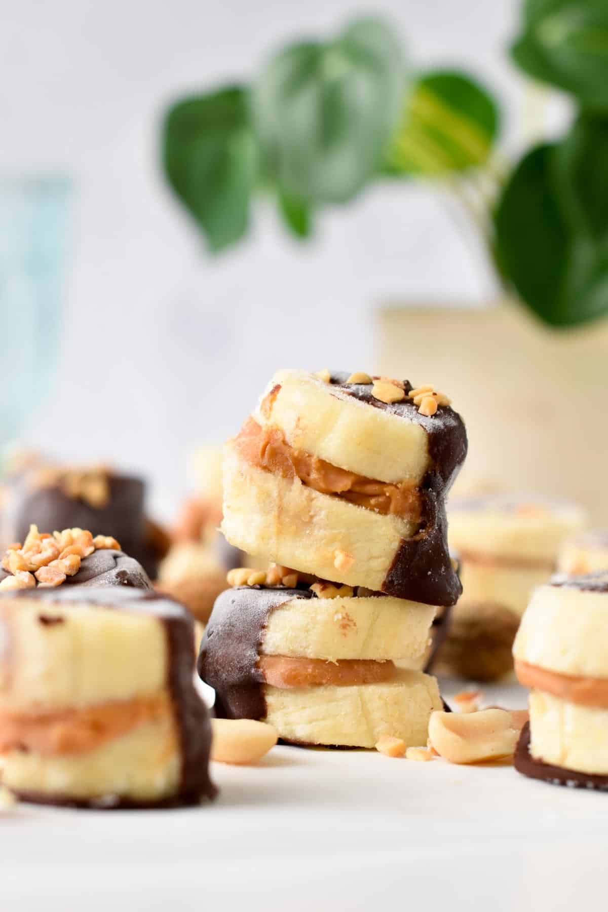 A stack of banana bites filled with peanut butter in the center and half covered with dark chocolate.