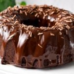 a chocolate Bundt Cake on a cake stand with drippy chocolate ganache